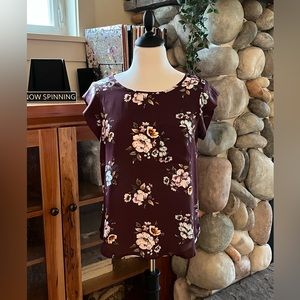 Burgundy and floral print blouse with cap sleeves and front pocket.